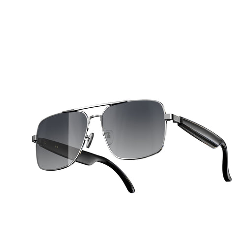 A pair of aviator-style sunglasses with a silver metal frame, dark gray gradient lenses, and black temple arms, shown from a three-quarters angle on a plain white background.